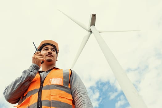 Engineer working on a wind farm atop a hill or mountain in the rural. Progressive ideal for the future production of renewable, sustainable energy. Energy generation from wind turbine.