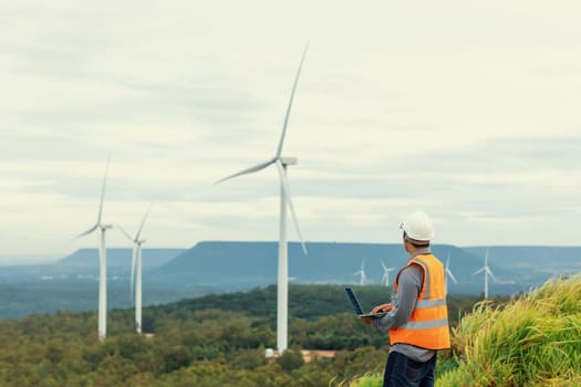 Engineer working on a wind farm atop a hill or mountain in the rural. Progressive ideal for the future production of renewable, sustainable energy. Energy generation from wind turbine.