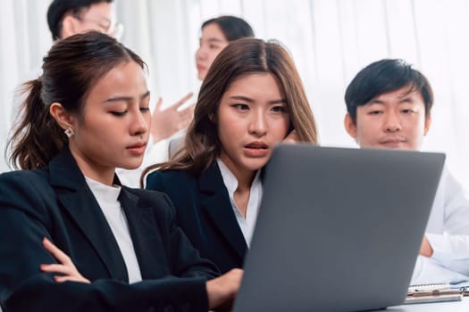 Focused businesspeople using laptop working on data analysis with serious facial expression in corporate environment at harmony office. Struggle in financial strategy planning at meeting desk.