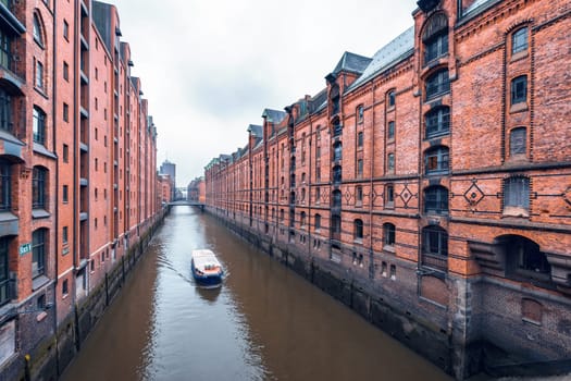 Touristic cruise boat on a channel with bridges in the old warehouse district Speicherstadt in Hamburg, Germany