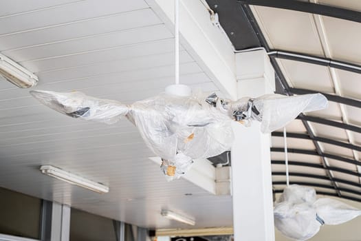 Metal and white ceiling and large fans are covered for open air industry building.