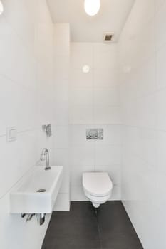 a white bathroom with black tile flooring and a toilet in the corner, there is a mirror on the wall