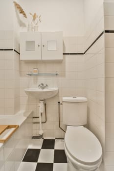 a small bathroom with black and white tiles on the floor, sink, toilet, and mirror in one room