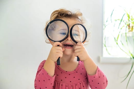 Child explore the world under a magnifying glass. Selective focus. Kid.