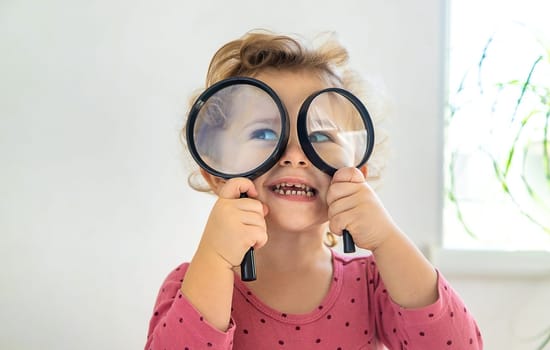 Child explore the world under a magnifying glass. Selective focus. Kid.