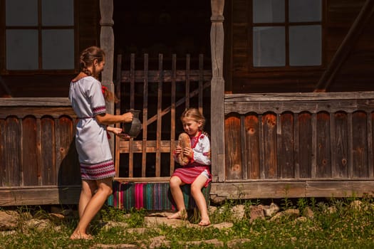 mother and daughter in Ukrainian folk dresses on the threshold of the house.