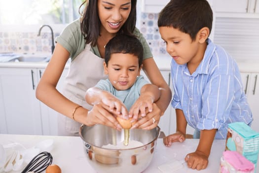 Mom, kids and kitchen for baking, cooking or cake in home while excited, happy or smile on face. Mother, boy and children in house to crack egg for learning of food, cookies or muffins in Los Angeles.
