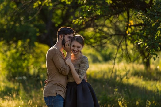 man tells in his ear the secret of his girlfriend walking in the park