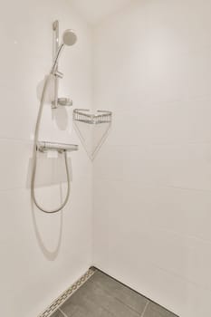 a shower in a white tiled bathroom with grey tile flooring and wall mounted handrails on the walls