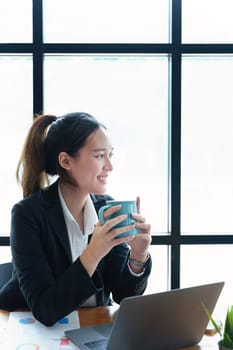 Portrait of a young woman drinking coffee while using a computer.