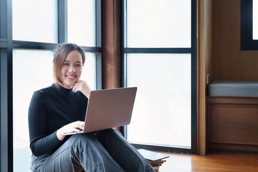 Portrait of an Asian woman using a computer to study online and drinking coffee while video conference.