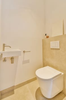 a bathroom with a white toilet and beige tiled floor in the photo is taken to the right, there is a mirror on the