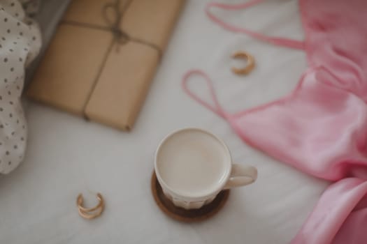 Light cozy bedroom, Coffee cup and gift or book on the bed. Good morning