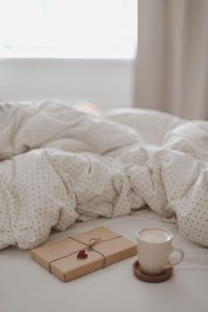 Light cozy bedroom, Coffee cup and gift or book on the bed. Good morning