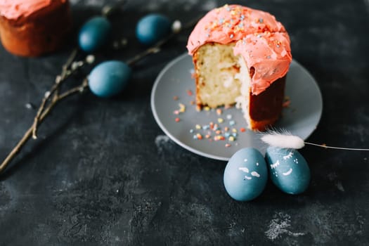 Plate with tasty Easter cake, eggs and willow branches on dark background. High quality photo