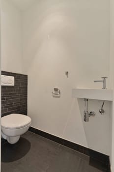 a white toilet in a bathroom with black and white tiles on the wall behind it is an open shower stall