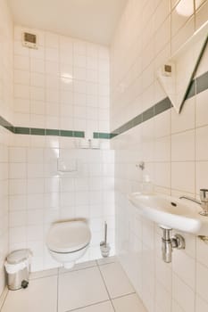 a small bathroom with white tiles and green trim on the walls, along with a toilet in the corner next to the sink