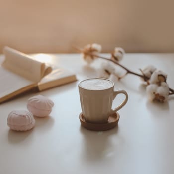 coffee cup, cotton flower, open book on a white table background top view. minimal home interior decor.