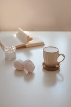 coffee cup, cotton flower, open book on a white table background top view. minimal home interior decor.