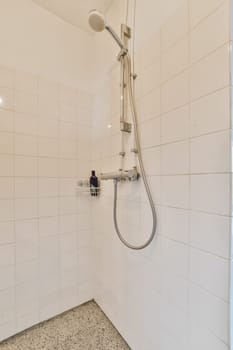 a bathroom with white tiles on the walls and shower head mounted to the wall next to it is a tiled floor