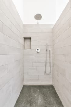 a walk - in shower with gray tile flooring and white wall tiles on the walls there is an overhead shower head