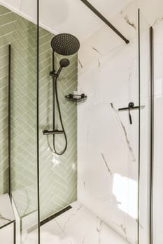 a bathroom with green tiles and black shower faucets on the wall next to it is a white tiled floor