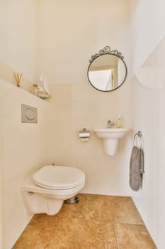 a bathroom with a toilet, sink and mirror on the wall next to it is a towel hanging on the shelf