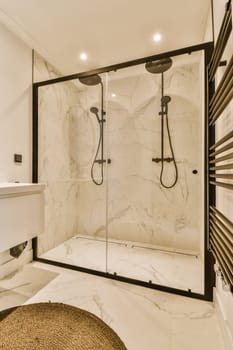 a modern bathroom with marble flooring and black trim on the shower door, along with a round rug in front