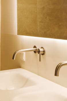 a bathroom sink with two faucets on the wall and a mirror in the corner to the left side