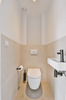 a toilet in the corner of a bathroom with beige tiles on the walls, and a white sink next to it
