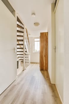 an empty room with wood flooring and wooden staircase leading up to the second floor in a white wall is on the right side