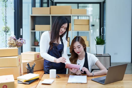 Starting small business two entrepreneur of independent Asian woman smiling using computer laptop with cheerful success of online marketing package box items and SME delivery concept.