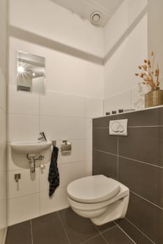 a white toilet in a small bathroom with tiled walls and floor tiles on the wall, there is a mirror above it