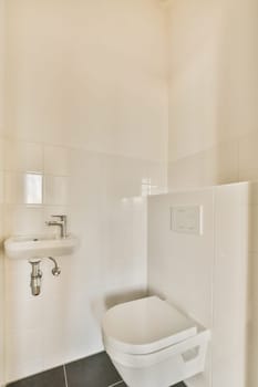 a white toilet in a bathroom with black tiles on the floor and wall behind it is a mirror above the toilet