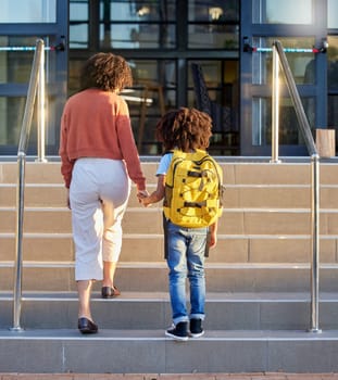 Mother, child and holding hands at school building, education with backpack and ready to learn at academy. Learning, study and student, black woman support kid for first day back to school