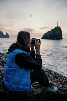 Woman travel sea. Happy tourist taking picture outdoors for memories. Woman traveler looks at the edge of the cliff on the sea bay of mountains, sharing travel adventure journey.