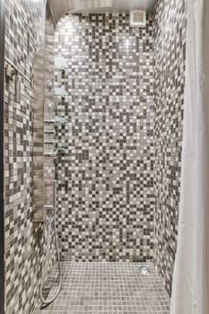 a tiled bathroom with white and gray tiles on the wall, shower stall and toilet in the background is black and white