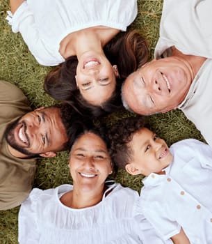 Big family, face and portrait smile above relaxing in quality bonding time together on the grass in the outdoors. Happy family smiling in joyful happiness lying in relax for summer break in the park.