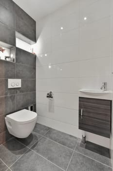 a modern bathroom with grey tile flooring and white tiles on the walls, along with a wall mounted toilet