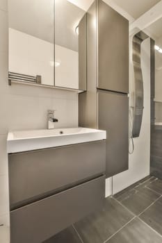 a modern bathroom with grey tile flooring and white cabinets in the shower stall is visible on the right side