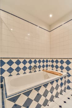 a tiled bathroom with blue and white tiles on the walls, along with a large bathtub in the corner