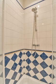 a bathroom with blue and white tiles on the walls, shower head in the corner to the wall is tiled