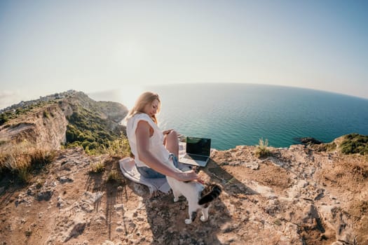 Woman sea laptop. Business woman in yellow hat working on laptop by sea. Close up on hands of pretty lady typing on computer outdoors summer day. Freelance, digital nomad, travel and holidays concept.