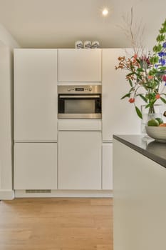 a kitchen with white cabinets and flowers in a vase on the counter top next to an oven, microwave and dishwasher