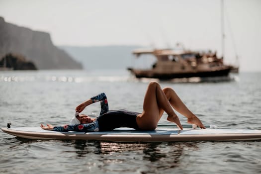 Woman sup yoga. Middle age sporty woman practising yoga pilates on paddle sup surfboard. Female stretching doing workout on sea water. Modern individual hipster outdoor summer sport activity