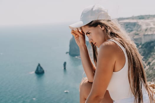 Woman travel sea. Young Happy woman in a long red dress posing on a beach near the sea on background of volcanic rocks, like in Iceland, sharing travel adventure journey