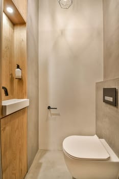 a bathroom with a toilet, sink and light fixture on the wall next to the toilet is a wooden cabinet