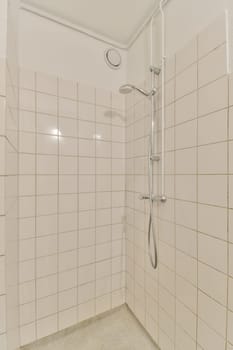 a bathroom with white tiles on the walls and shower head mounted to the wall in front of the bathtub