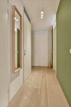 an empty room with green walls and wood flooring on the left side of the room, there is a mirror in the wall