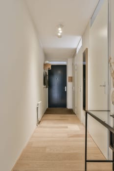 a long hallway with wood flooring and white walls in the room is framed by a large mirror on the wall